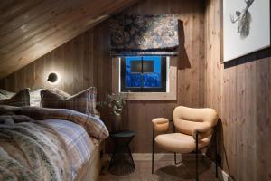 a bedroom with a bed and a chair and a window at FJELLRO Private Alpine Lodge Høgevarde in Flå