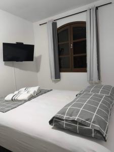 a bedroom with a bed and a flat screen tv at Casinha Guest House in Saquarema
