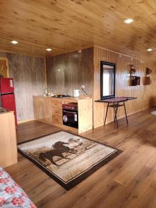 a room with wooden walls and a table and a rug at Cabaña monoambiente in Quellón