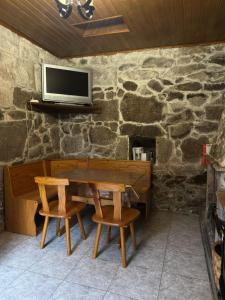 a table with two chairs and a tv on a stone wall at Casa Rural Melon in Melón