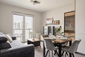 a living room with a table and a couch at Hygge Amber Aparts - 9th floor in Gdańsk Letnica