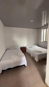 two beds in a room with white walls at Casa Turística Samanta in Buga +4 photos