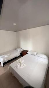 two beds in a room with white walls at Casa Turística Samanta in Buga