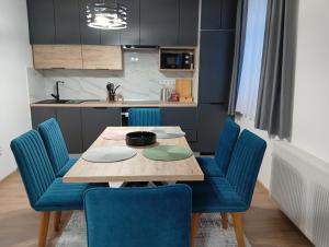 a dining room with a wooden table and blue chairs at Kuca za odmor PETAR u blizini Parka prirode PAPUK in Lisičine