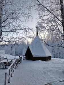 a barn covered in snow next to a fence at Majoitus Fox in Kuopio