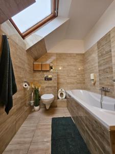 a bathroom with a tub and a toilet and a window at Keller Apartman in Cserszegtomaj