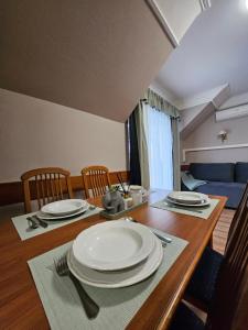 a dining room table with white plates and chairs at Keller Apartman in Cserszegtomaj