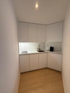 a kitchen with white cabinets and a sink at Wasserfall - Zentrum - Balkon - Seeblick - Küche in St. Moritz