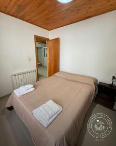 a bedroom with a bed with two towels on it at Lizkar Alojamientos in Esquel