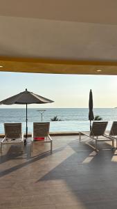 a patio with chairs and an umbrella and the ocean at Sunset view luxury in Cedro