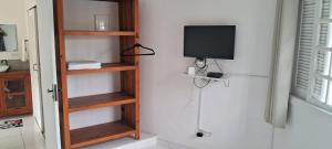 a room with wooden shelves and a tv on a wall at Kasa Mare studios Maresias in São Sebastião