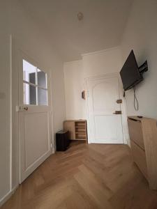 an empty room with a white door and a television at Le Cocon Dijonnais - Cours Cambronne in Dijon