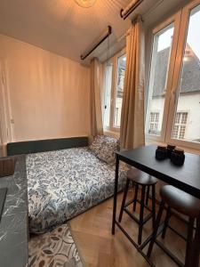 a room with a bed and a table and windows at Le Cocon Dijonnais - Cours Cambronne in Dijon