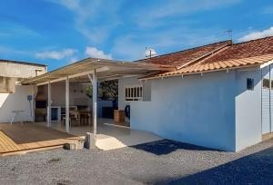 a detached house with a roof over a patio at Villa Di Mare 2 - Pool, fire pit, and barbecue grill in São Francisco do Sul