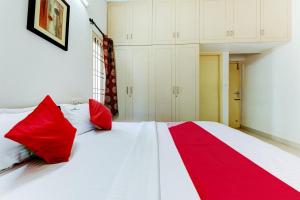 a red and white bed with red pillows on it at Hotel O J2 Service Apartment in Chennai