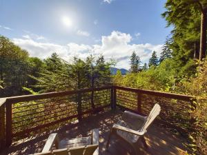 a deck with chairs and a fence and trees at Treetop Retreat w Fire Pit in Juneau