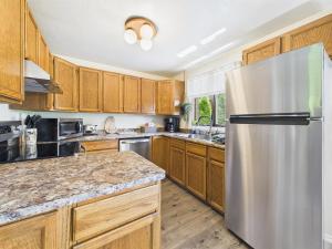 a kitchen with wooden cabinets and a stainless steel refrigerator at Treetop Retreat w Fire Pit in Juneau