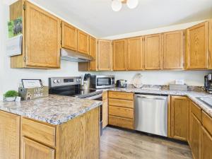 a kitchen with wooden cabinets and stainless steel appliances at Treetop Retreat w Fire Pit in Juneau