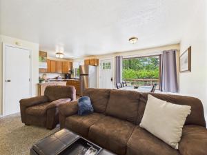 a living room with a brown couch and a kitchen at Treetop Retreat w Fire Pit in Juneau