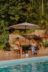 two women sitting under an umbrella next to a pool at Hotel La Casablanca Tayrona in Calabazo