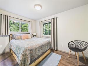 a bedroom with a bed and a chair and two windows at Sunny Point 2BR with Deck & Mountain Views in Juneau +9 photos
