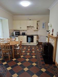 a kitchen with a table and chairs and a kitchen with white cabinets at Teach Kitty Con in Dungloe