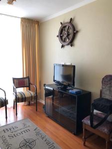 a living room with a flat screen tv and chairs at Departamento familiar in La Serena