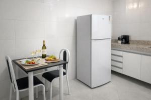a kitchen with a table and a white refrigerator at Lar Urbano in Manhuaçu