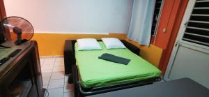 a small bed in a room with a fan at La Case Saint-Pierre in Saint-Pierre