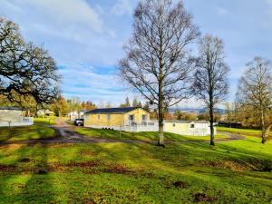 a house in a field with trees and a road at 10 lochview in Moffat