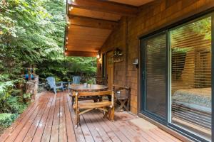 a wooden deck with a table and chairs on it at JDF Waystation Cabin - Garden View - Pet Friendly in Port Renfrew
