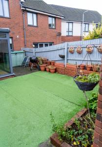 a backyard with green grass and potted plants and a fence at Vyn's Holiday home - Sleeps 6 in Cardiff