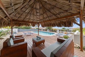 a patio with a large straw umbrella and a pool at Villa Strelitzia in Dorp Soto