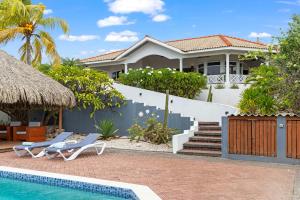 a villa with a swimming pool and a house at Villa Strelitzia in Dorp Soto