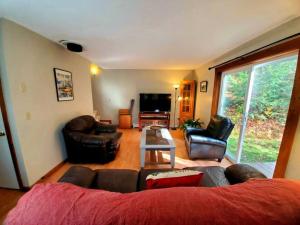 a living room with leather furniture and a large window at Fiddlehead Greens in Warren