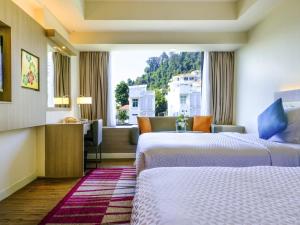 a hotel room with two beds and a window at Mercure Penang Beach in George Town