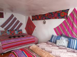 two beds in a room with colorful blankets at Wiñay UTA lodge in Puno