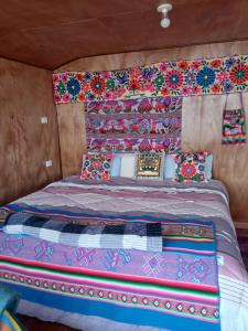 a bed with colorful blankets and pillows on it at Wiñay UTA lodge in Puno +7 photos