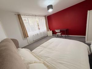 a bedroom with a white bed and a red wall at Precious House 4 in Leicester