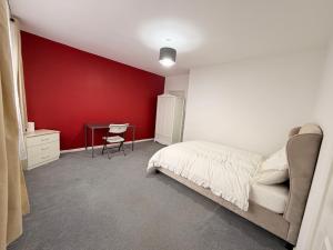 a bedroom with a red wall and a bed and a desk at Precious House 4 in Leicester +7 photos