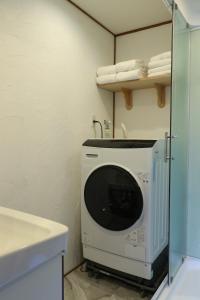 a washing machine in a bathroom next to a sink at 京都 大阪アクセス良好の和モダン民泊 静かで快適な宿泊施設です 京阪本線楠葉駅から徒歩圏内 急行特急停車駅で京都へ約30分 大阪へ約40分とアクセス良好です in Hirakata +21 photos
