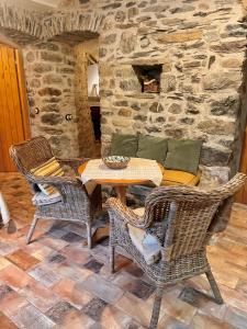 a patio with a table and chairs and a stone wall at Casa de piedra Siglo XVIII in Badaín +36 photos