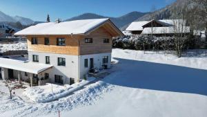 a house with snow on the ground in front at Servus in der Wiesenstrasse inklusive Chiemgaukarte in Ruhpolding