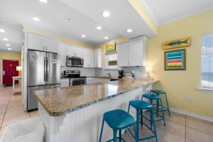a kitchen with white cabinets and blue bar stools at Marlin Key 4G by Youngs Suncoast in Orange Beach +25 photos