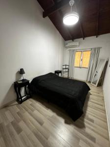a bedroom with a black bed and a wooden floor at El descanso in Ramallo +12 photos