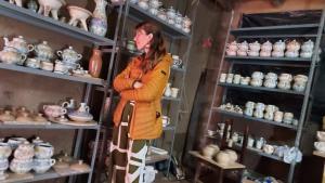 a woman standing in a shelf of pottery at Casa Mirita in Cajamarca