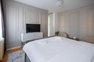 a bedroom with a white bed and a flat screen tv at Apartman Helena - Self check in in Osijek