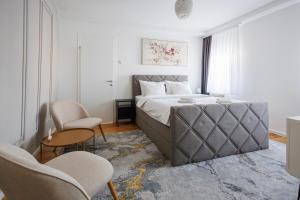a bedroom with a large bed with two chairs at Apartman Helena - Self check in in Osijek