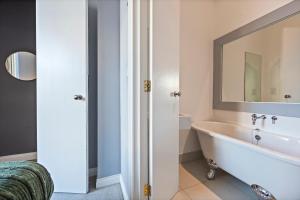 a bathroom with a tub and a mirror at Premium Beach Front with Balcony! 2 En-Suites & Spacious By Stay Aura Vacation Rental Brighton & Hove in Brighton & Hove +37 photos