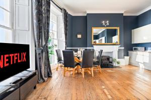 a living room with a table and chairs and a television at Premium Beach Front with Balcony! 2 En-Suites & Spacious By Stay Aura Vacation Rental Brighton & Hove in Brighton & Hove